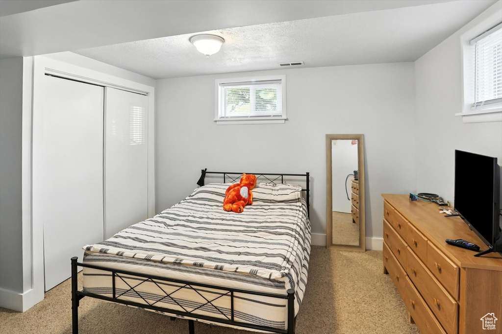 Bedroom featuring light carpet, a closet, and a textured ceiling
