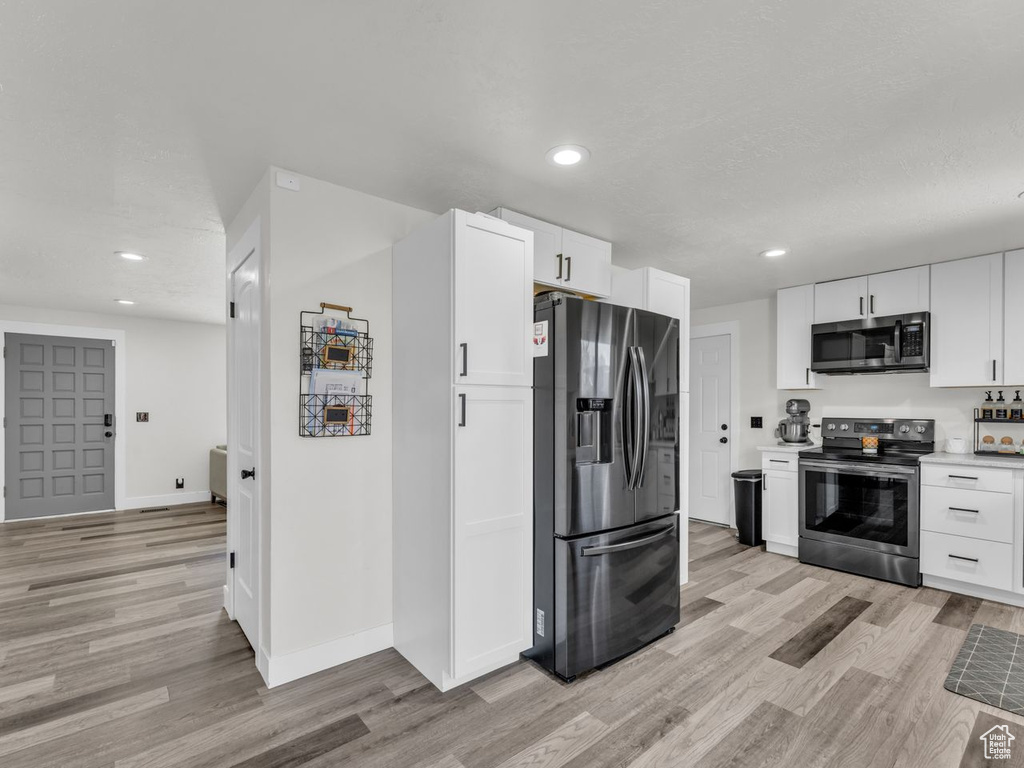 Kitchen featuring appliances with stainless steel finishes, light wood-type flooring, white cabinets, recessed lighting, and light countertops