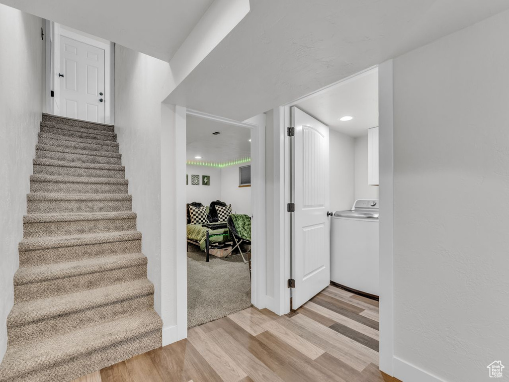 Stairs with washer / clothes dryer, wood finished floors, and recessed lighting