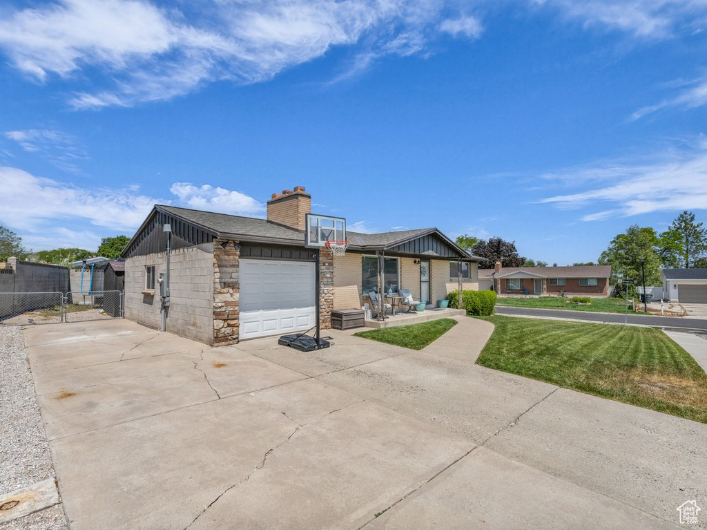 View of front of house featuring a garage, concrete driveway, a chimney, and board and batten siding