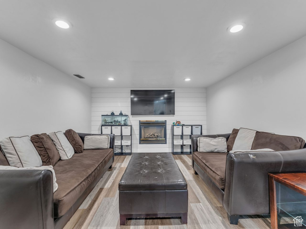 Living area with light wood finished floors, recessed lighting, and a glass covered fireplace