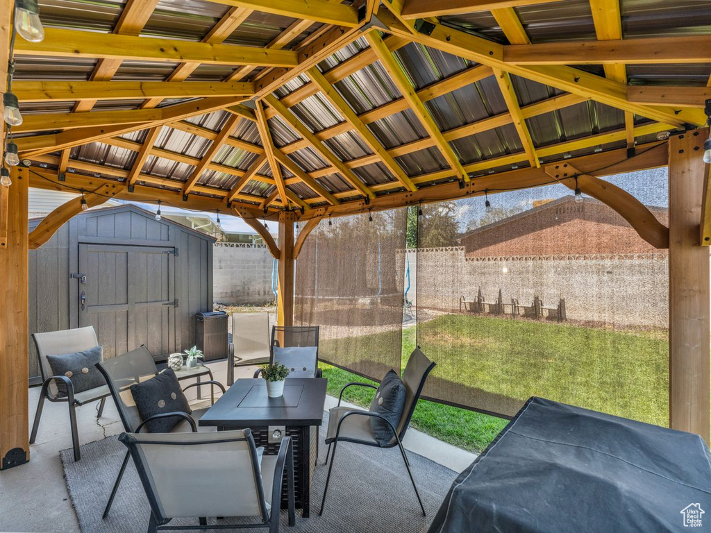 Fenced backyard with a storage shed, a gazebo, a patio, and outdoor dining space
