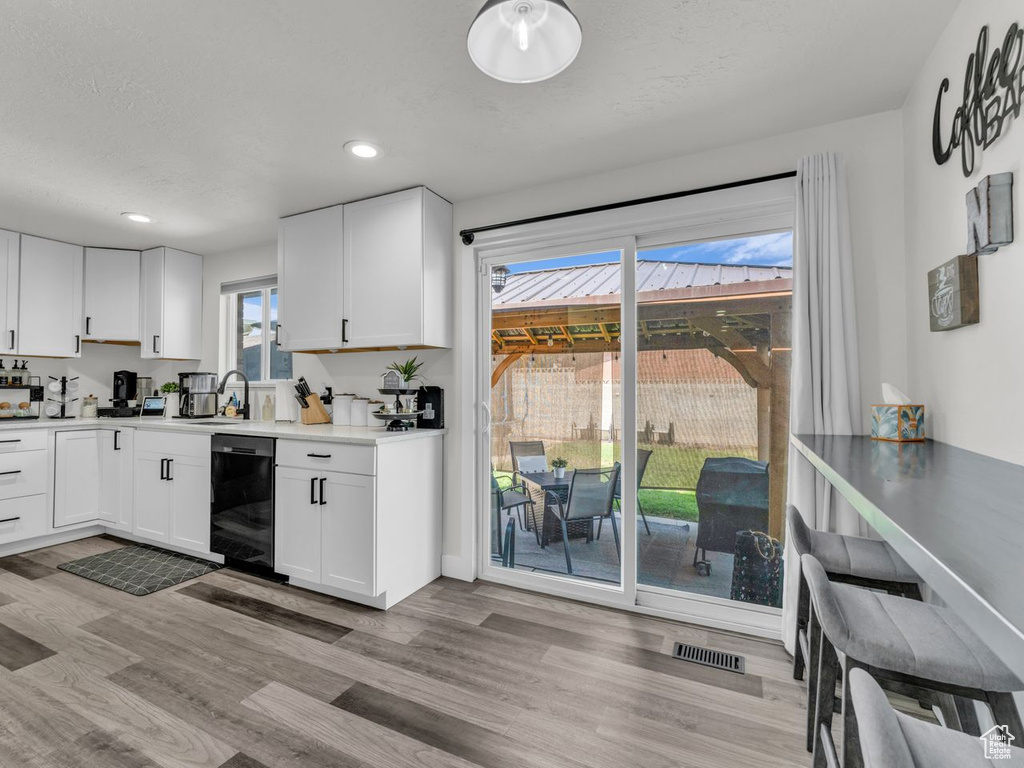Kitchen featuring dishwasher, light wood finished floors, white cabinetry, recessed lighting, and light countertops