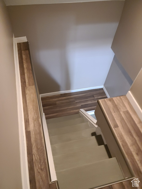 Stairway with wood finished floors and baseboards