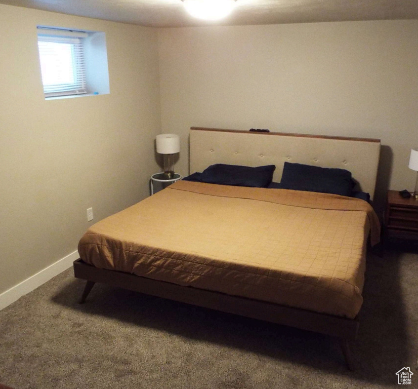 Bedroom with dark carpet and baseboards