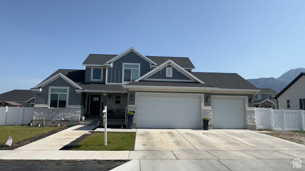 View of front of property with stone siding, driveway, a garage, and board and batten siding