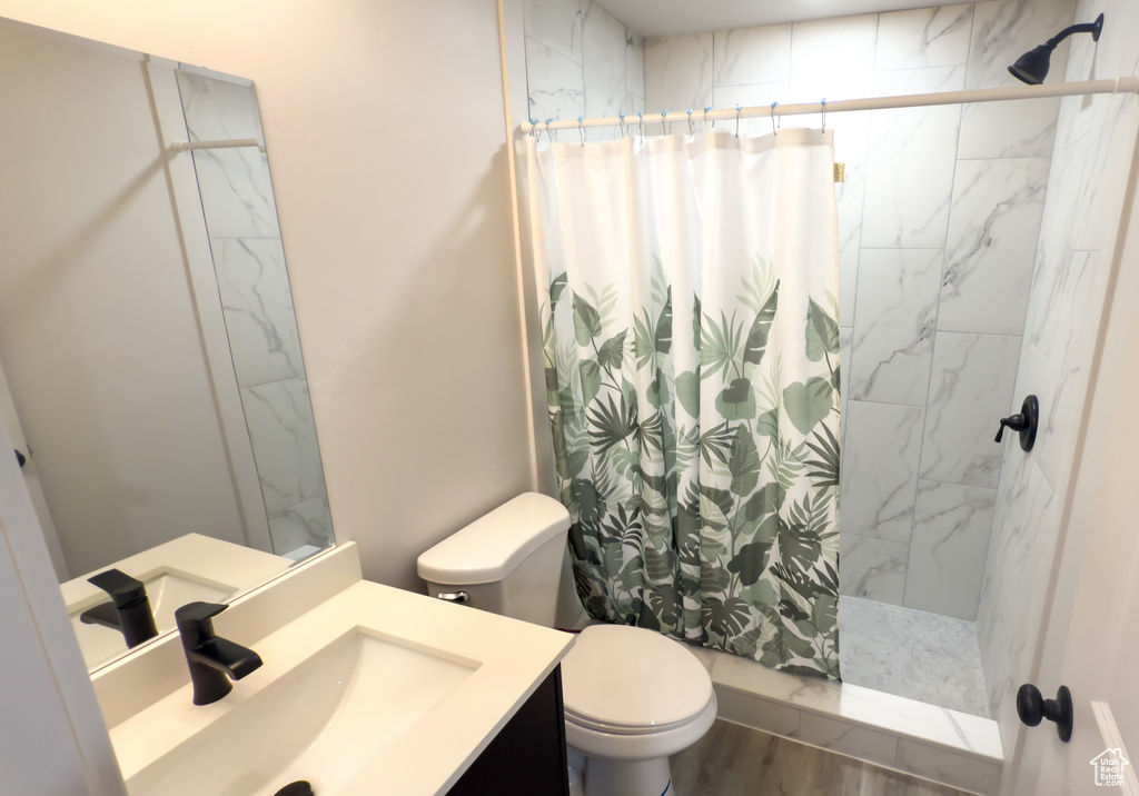 Full bath featuring a shower with shower curtain, vanity, and wood finished floors