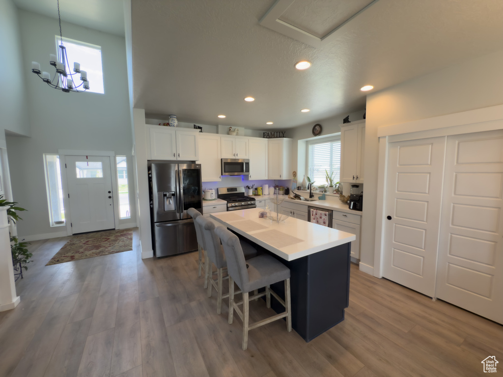 Kitchen with stainless steel appliances, white cabinetry, a kitchen island, recessed lighting, and a kitchen breakfast bar