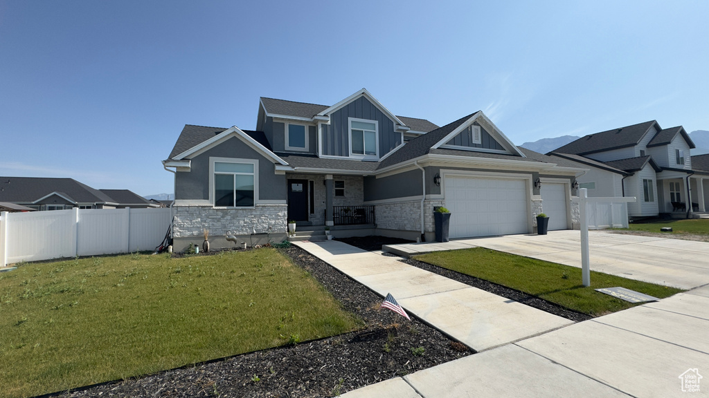 Craftsman house featuring concrete driveway, stone siding, an attached garage, board and batten siding, and a porch