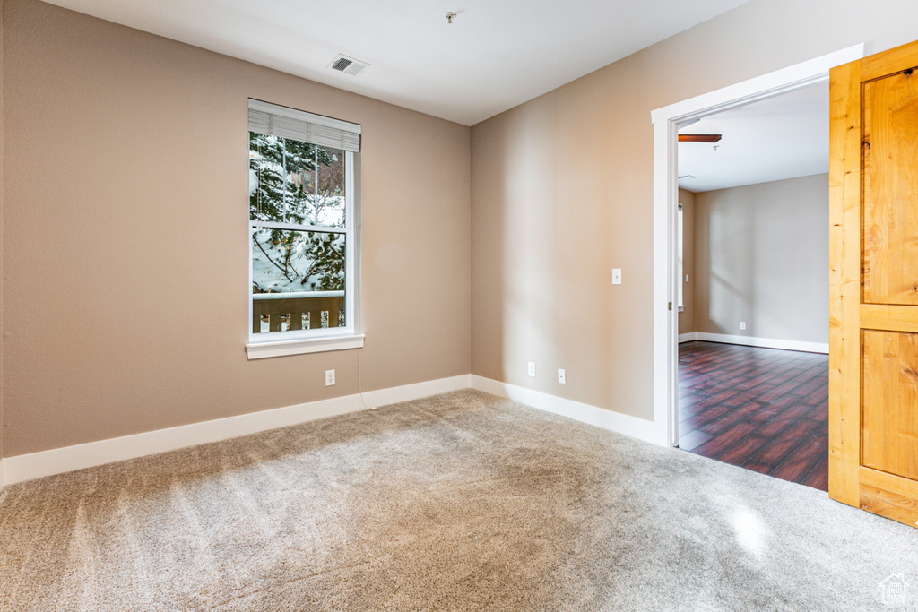 Carpeted spare room featuring baseboards and fire sprinkler in ceiling