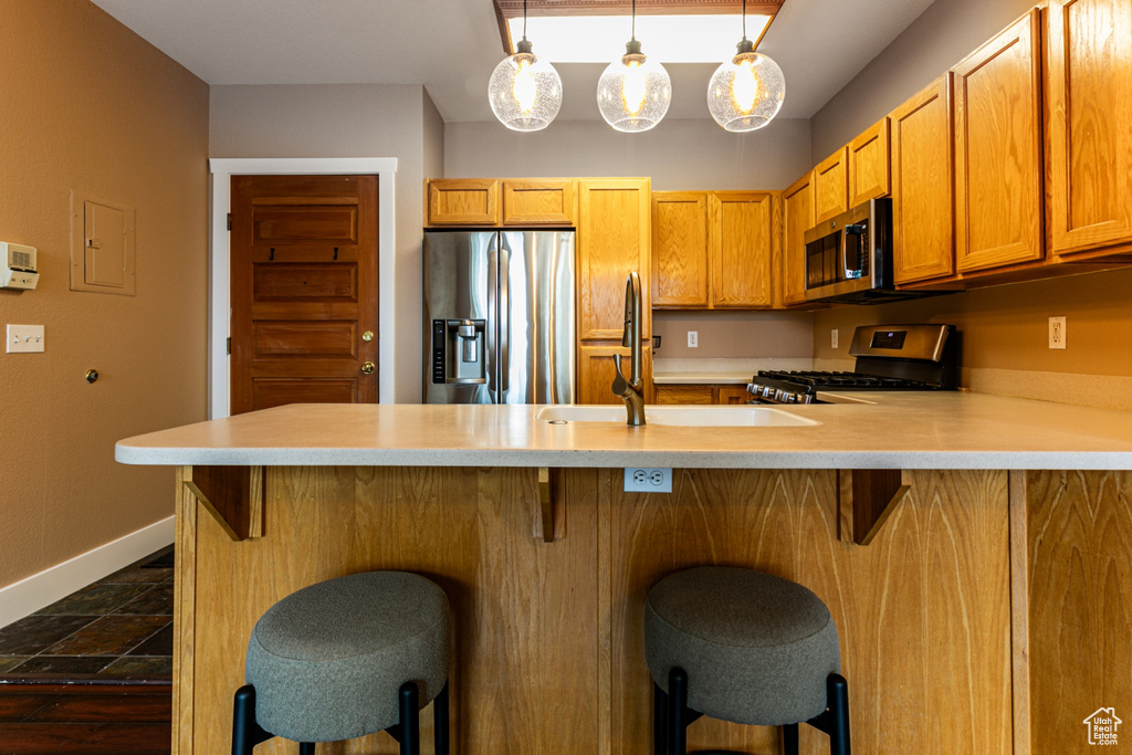 Kitchen with appliances with stainless steel finishes, light countertops, a peninsula, and dark stone finish flooring