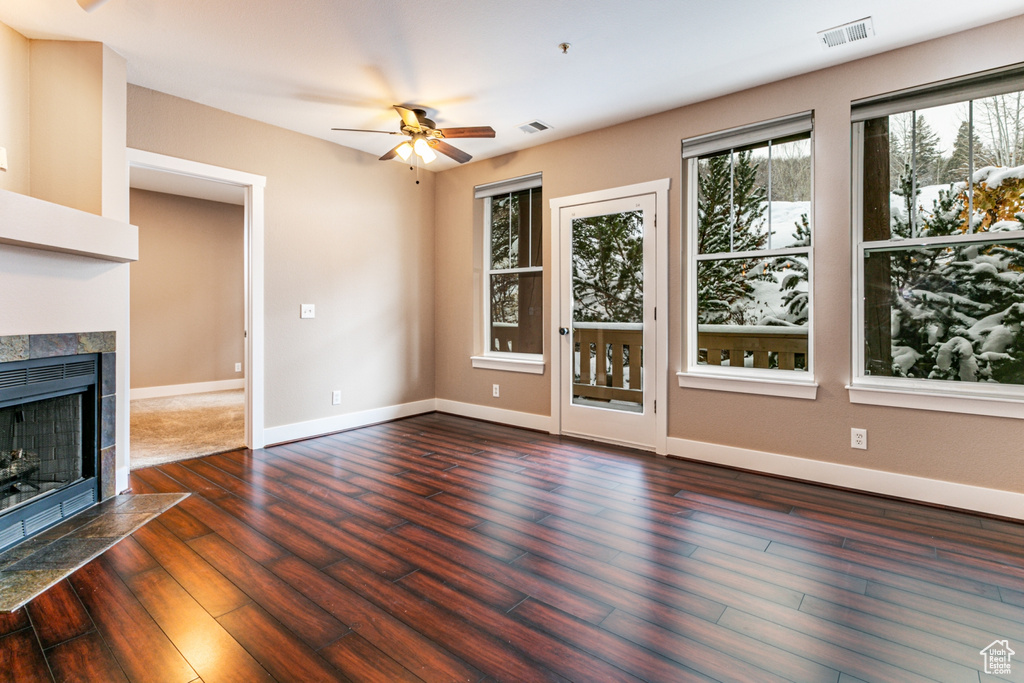 Unfurnished living room featuring a ceiling fan, wood finished floors, and a fireplace