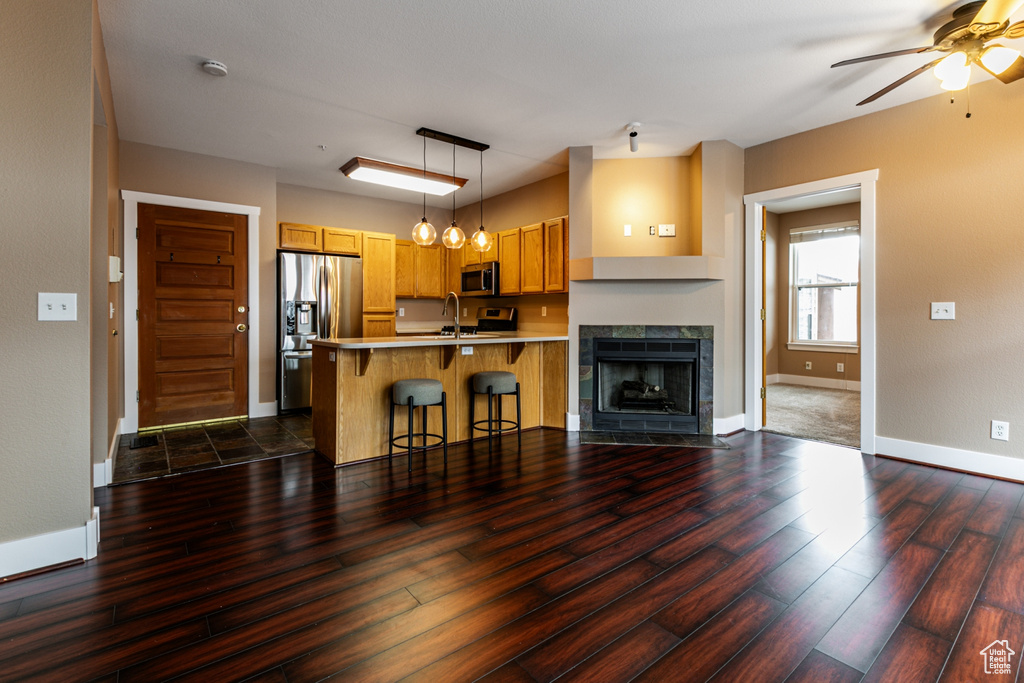 Kitchen featuring appliances with stainless steel finishes, a peninsula, dark wood finished floors, a breakfast bar area, and ceiling fan