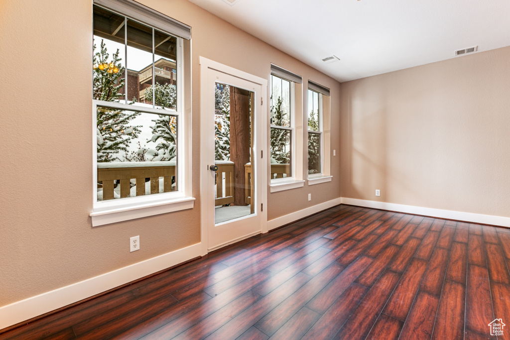 Spare room with baseboards and dark wood-type flooring