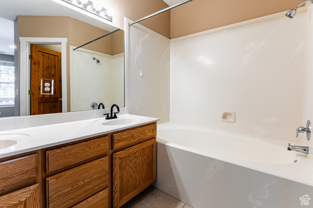 Full bathroom with double vanity, shower / bath combination, and tile patterned floors