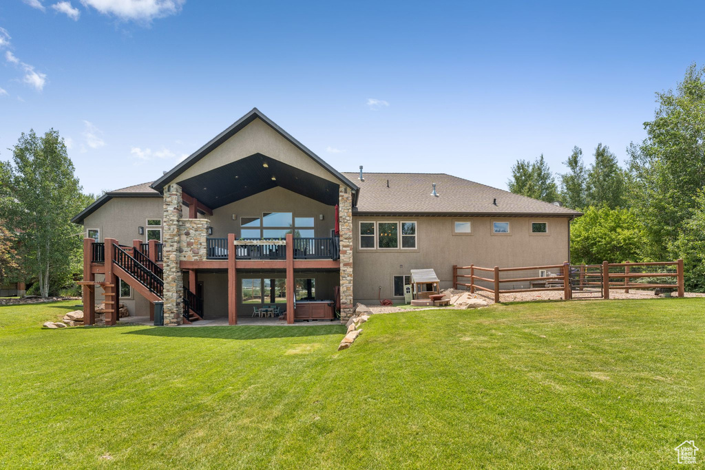 Back of property featuring a patio area, a wooden deck, a hot tub, and stairs