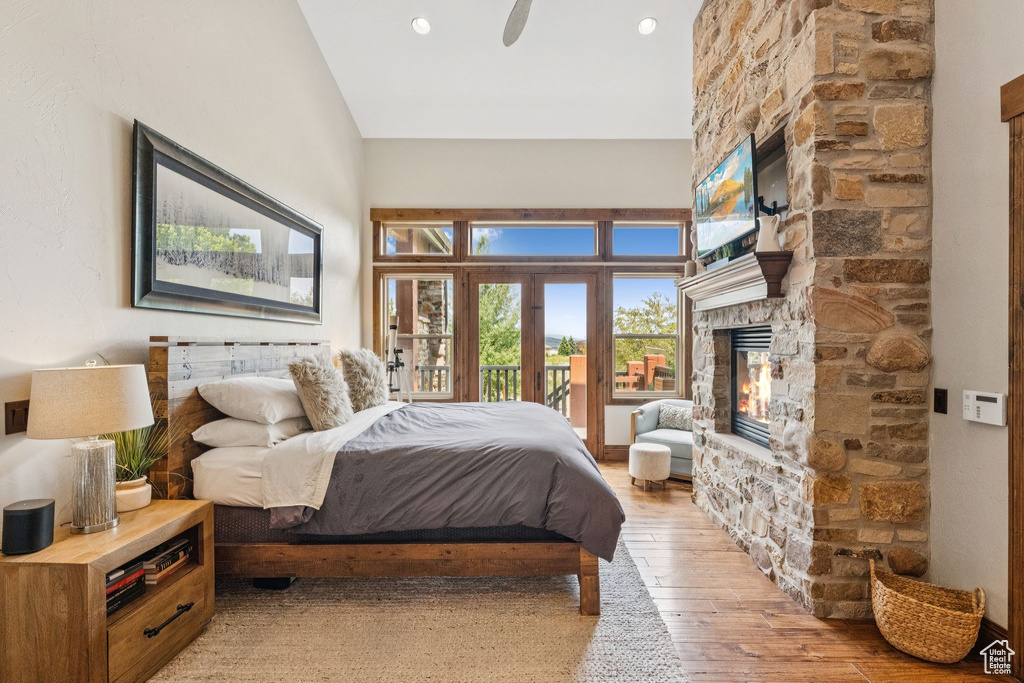 Bedroom featuring a fireplace, light wood-style flooring, access to exterior, a ceiling fan, and recessed lighting