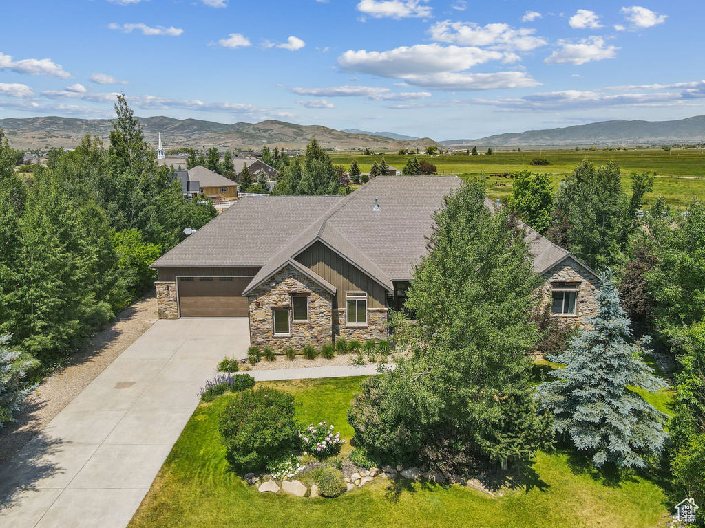 View of front of home featuring stone siding, concrete driveway, a garage, and a mountain view