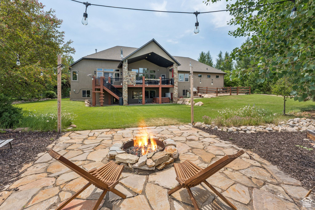 Back of house with a fire pit, a patio area, a deck, stairway, and a yard