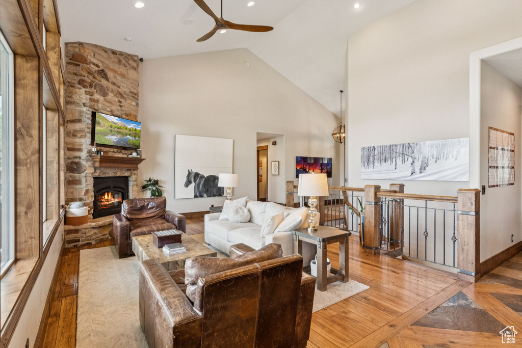 Living room featuring a ceiling fan, a fireplace, wood finished floors, recessed lighting, and high vaulted ceiling