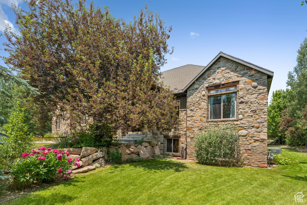 View of front of home featuring stone siding and a front lawn