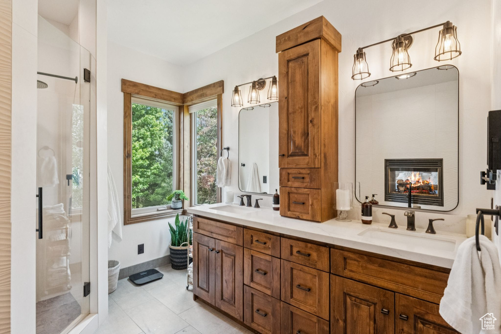 Bathroom featuring a shower stall, double vanity, a multi sided fireplace, and tile patterned floors