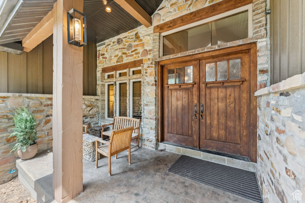 Doorway to property featuring stone siding, french doors, and a porch