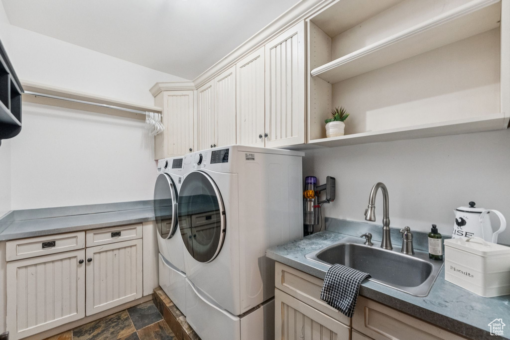 Laundry area featuring separate washer and dryer, cabinet space, and dark stone finish floors