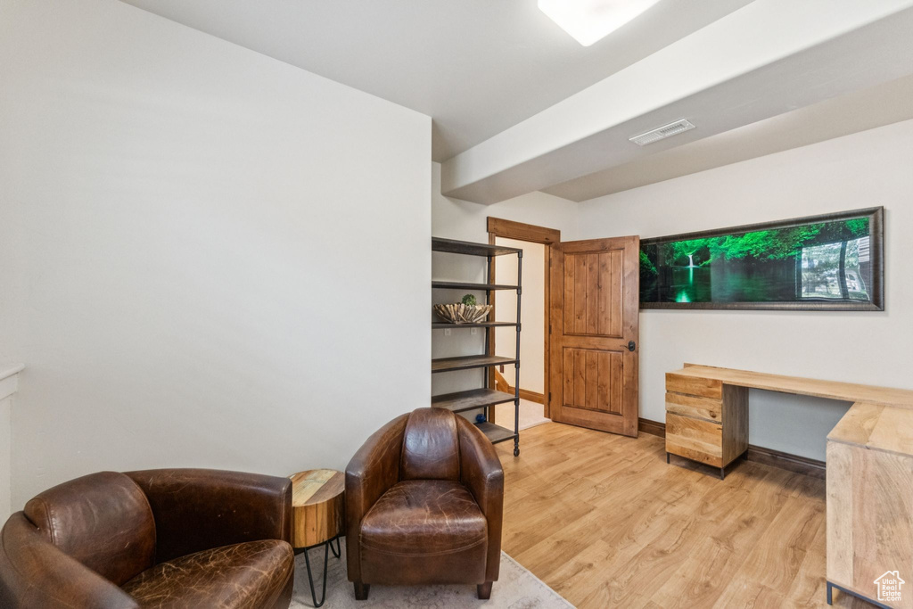 Sitting room with light wood-type flooring and a desk