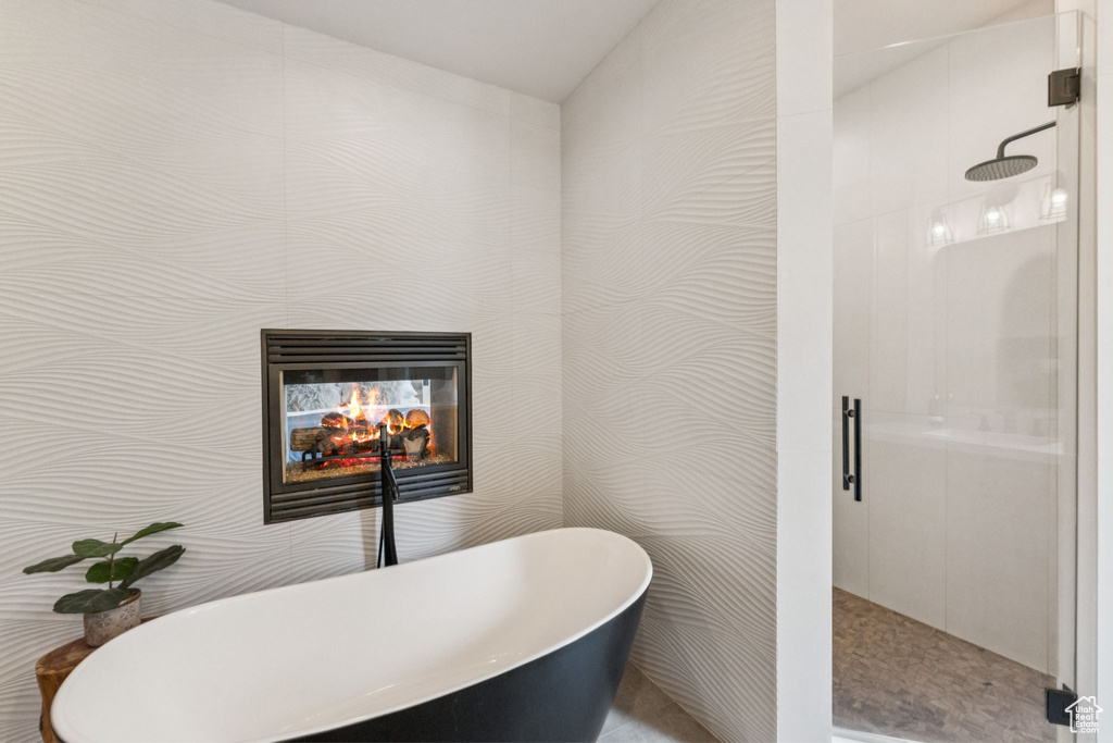 Bathroom with a stall shower, a tiled fireplace, and a freestanding tub