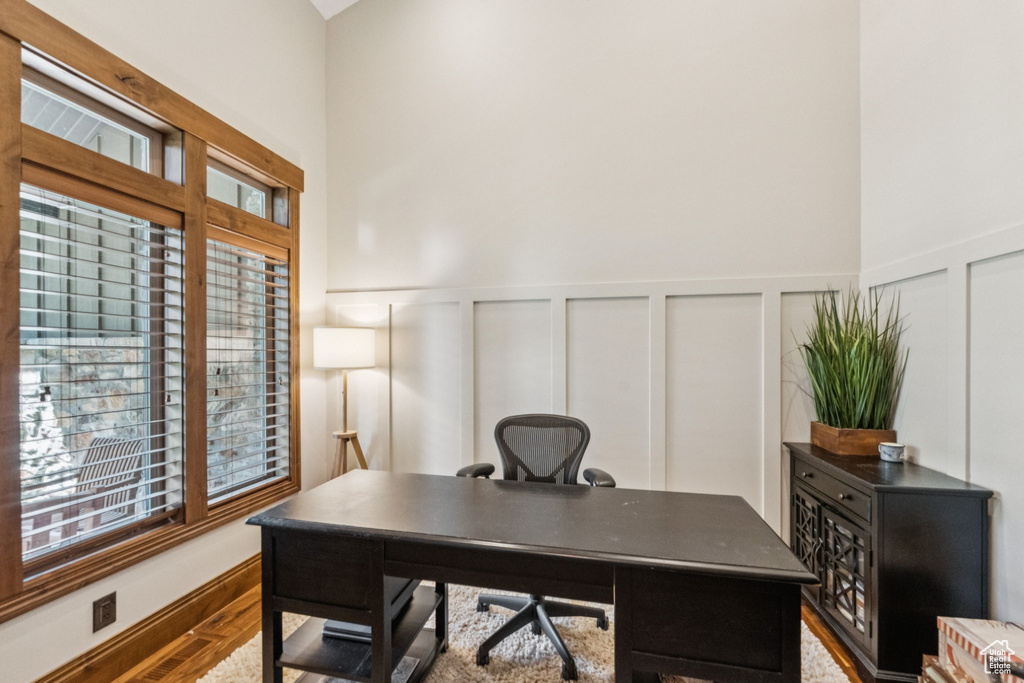 Office area with a decorative wall, plenty of natural light, wainscoting, and wood finished floors