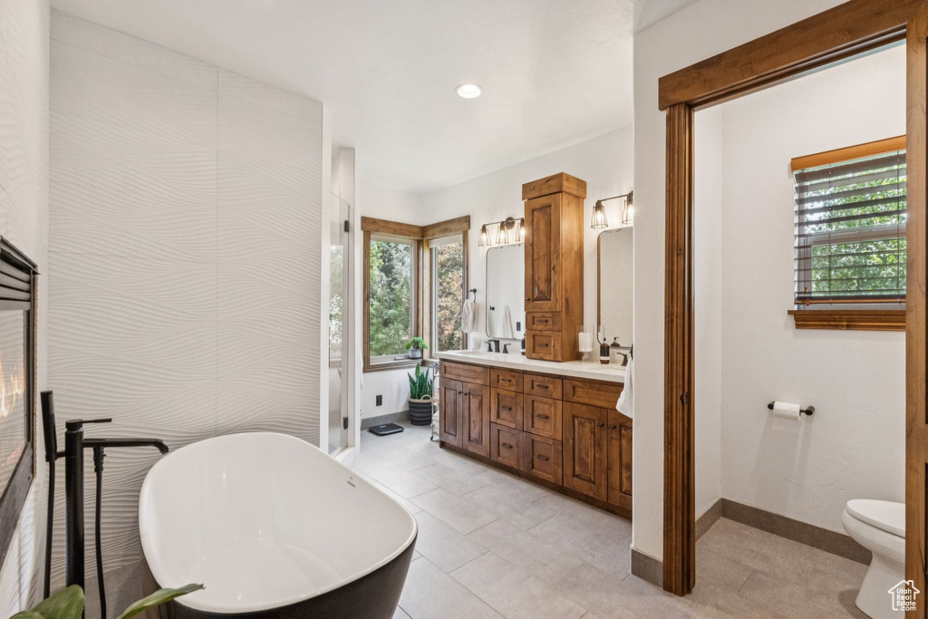 Full bathroom featuring double vanity, a freestanding tub, healthy amount of natural light, recessed lighting, and tile patterned flooring
