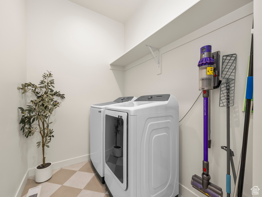 Washroom with washing machine and clothes dryer and light floors