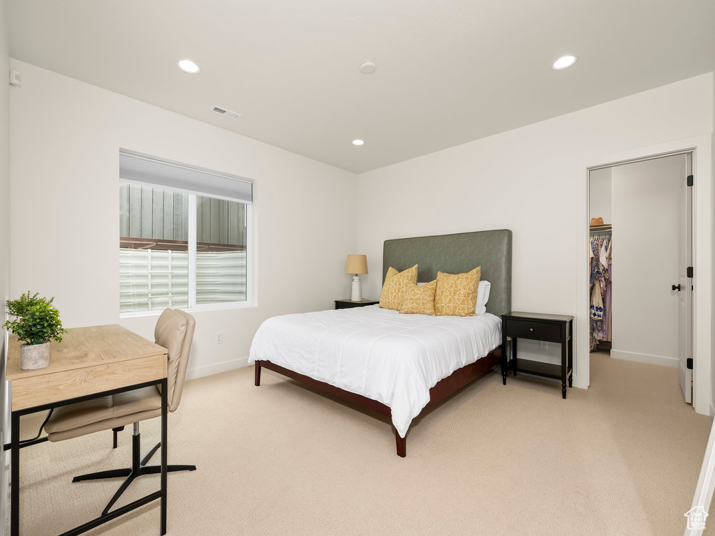 Bedroom with light colored carpet, recessed lighting, a walk in closet, and an office area