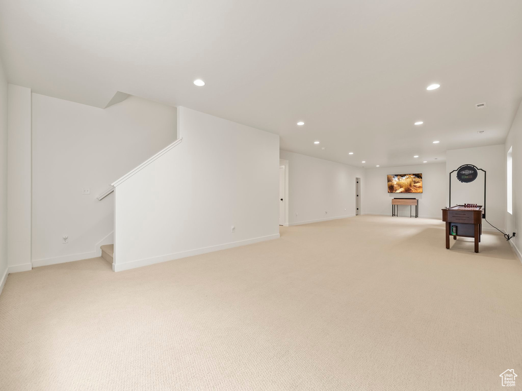 Below grade area with light carpet, recessed lighting, and stairway