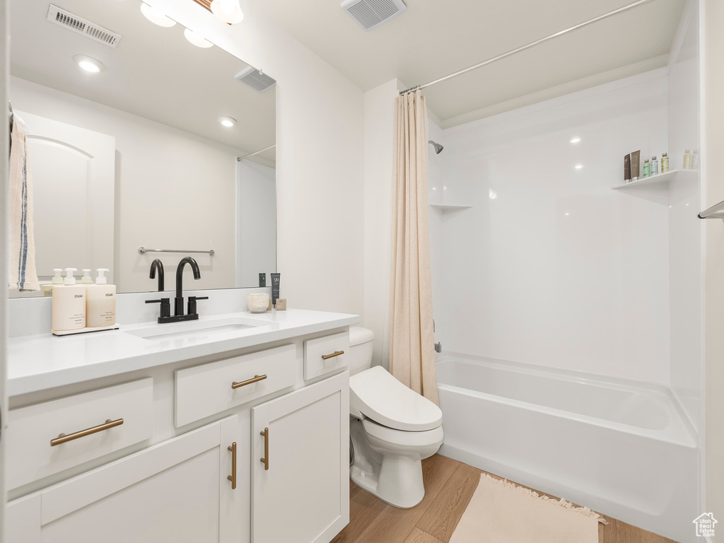 Full bathroom with vanity, wood finished floors, and shower / bath combo with shower curtain
