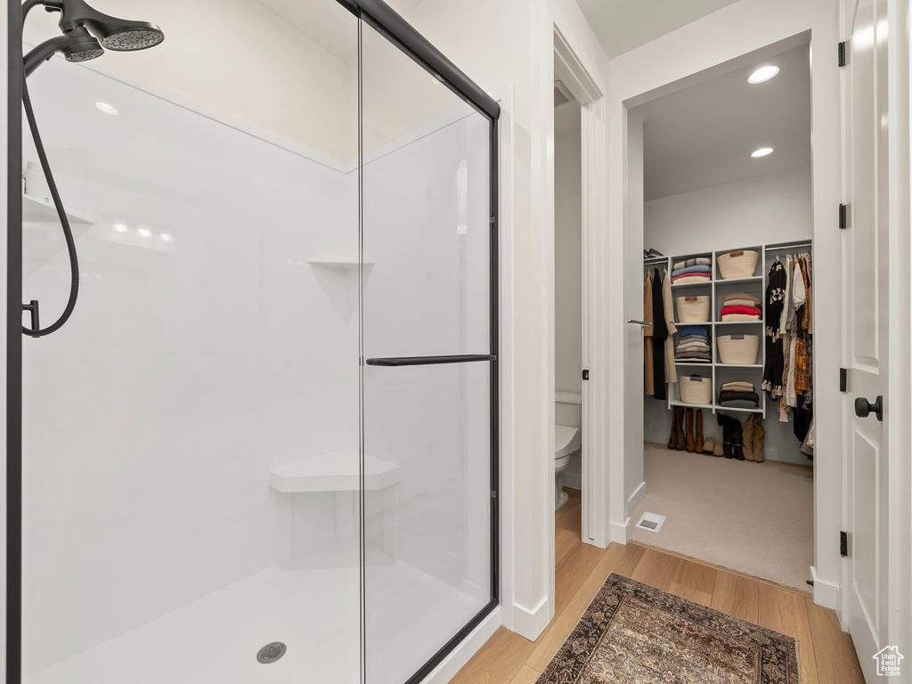 Full bath featuring a stall shower, wood finished floors, a spacious closet, and recessed lighting