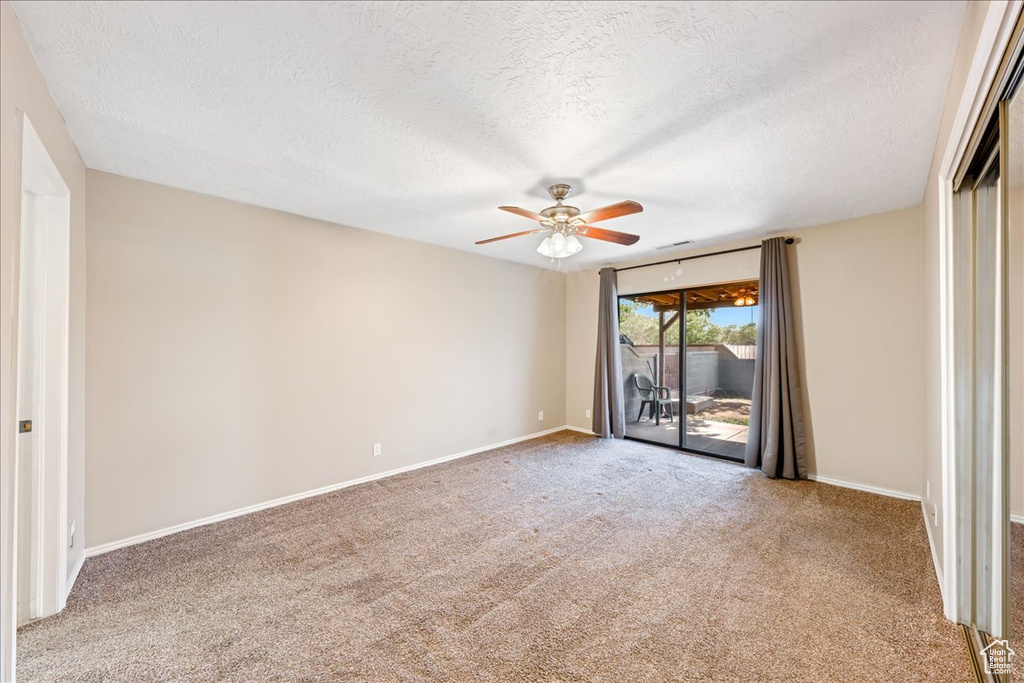 Carpeted empty room with a textured ceiling and a ceiling fan