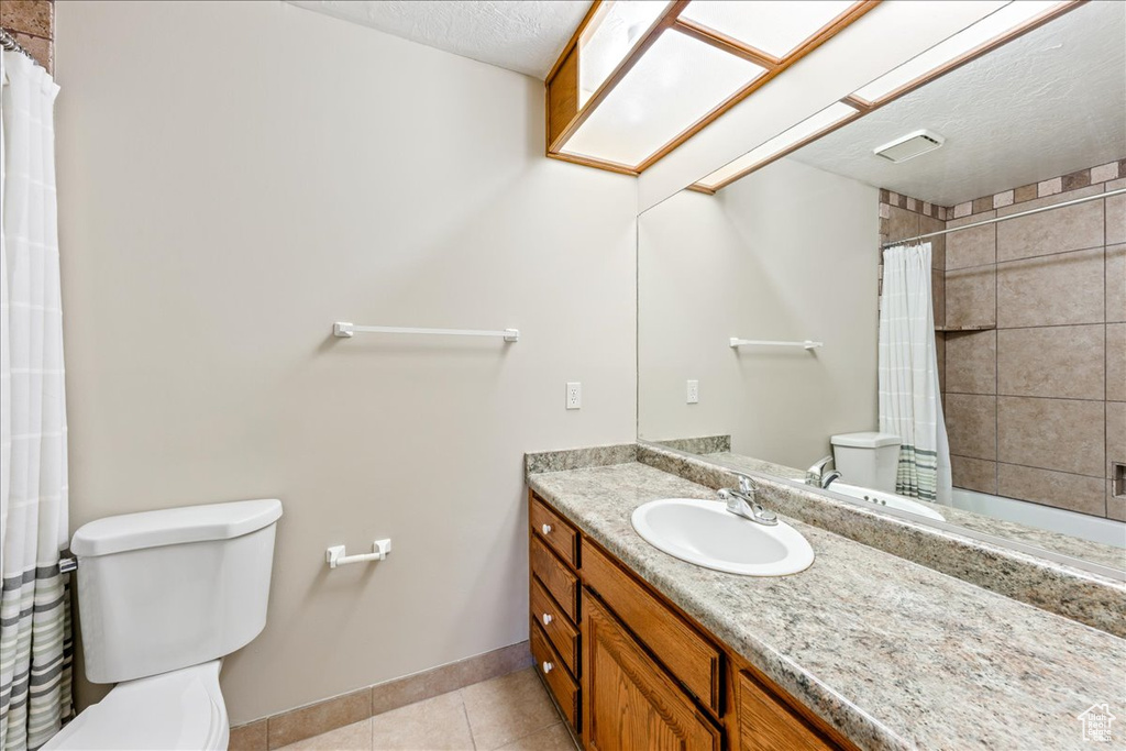 Full bathroom with tile patterned flooring, vanity, a shower with curtain, and a textured ceiling