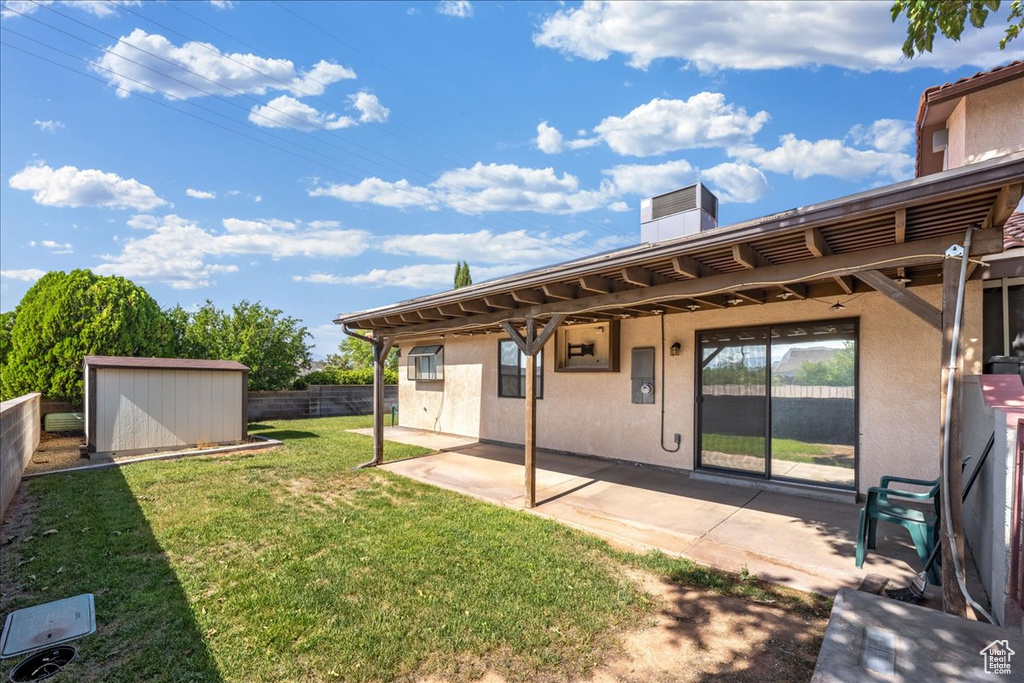 Rear view of property featuring a patio, stucco siding, a storage shed, and a chimney