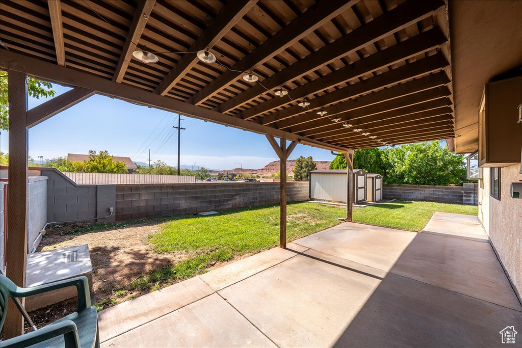 Fenced backyard with a patio area, a shed, and a mountain view
