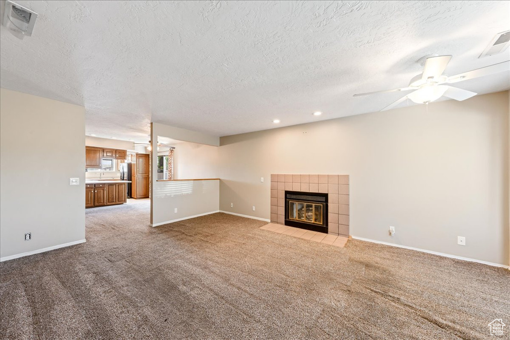 Unfurnished living room with light colored carpet, a textured ceiling, a fireplace, ceiling fan, and recessed lighting