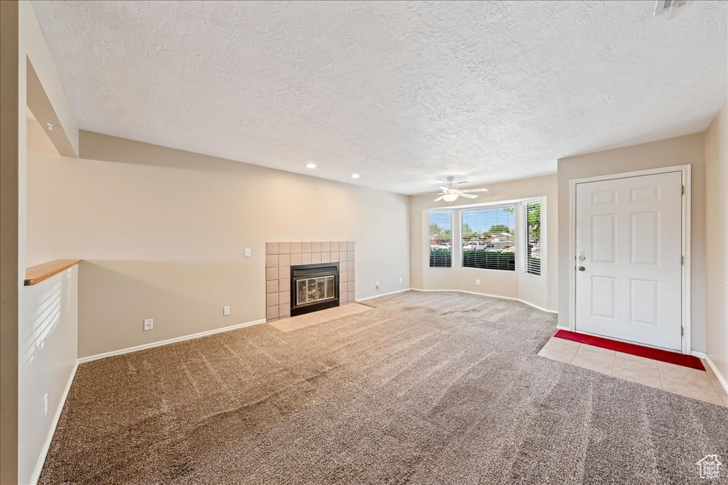 Unfurnished living room with a textured ceiling, carpet, a fireplace, a ceiling fan, and recessed lighting