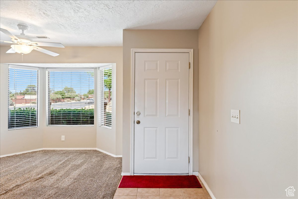 Entryway featuring ceiling fan, a textured ceiling, and light carpet