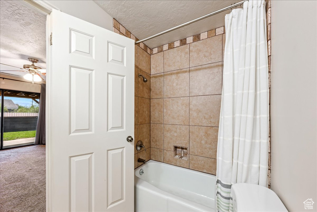 Full bath featuring a textured ceiling, shower / bath combo with shower curtain, and a ceiling fan