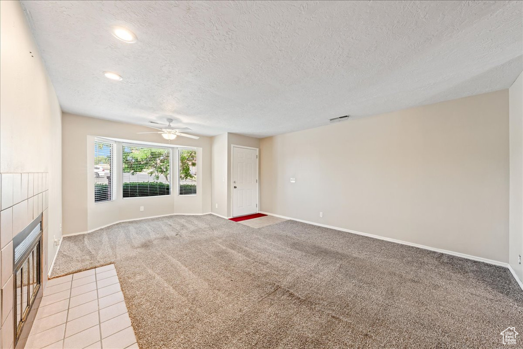 Unfurnished living room featuring a textured ceiling, a fireplace, light colored carpet, ceiling fan, and recessed lighting