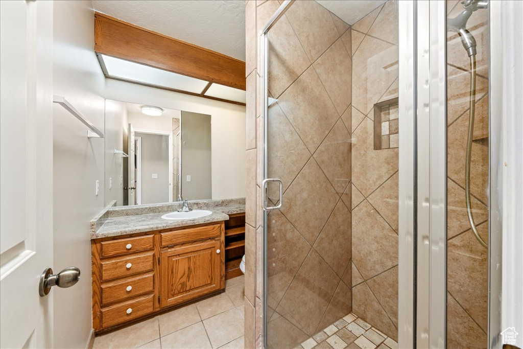 Full bathroom featuring vanity, a shower stall, and tile patterned flooring