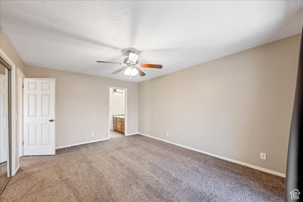 Unfurnished bedroom featuring carpet floors, ensuite bath, and a ceiling fan