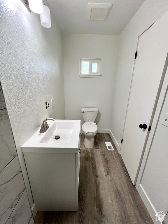 Half bathroom with wood finished floors and vanity