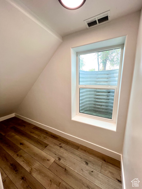 Additional living space with dark wood-style flooring and lofted ceiling